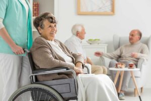 Two older adults and a caregiver touring a bright, comfortable assisted living common area.
